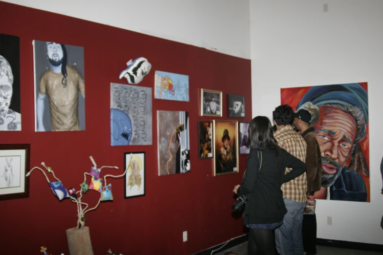 people are looking at artwork on a red wall