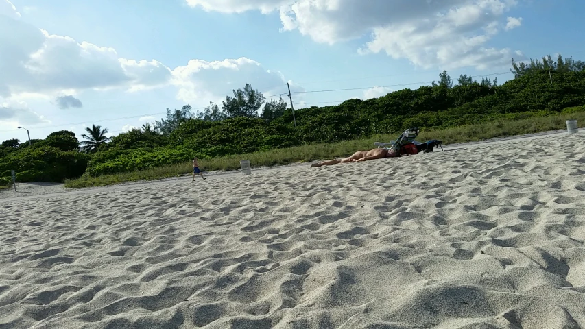 a person laying on a beach with a kite in the sky