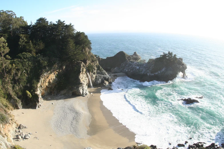 a sandy shore with some trees on the left