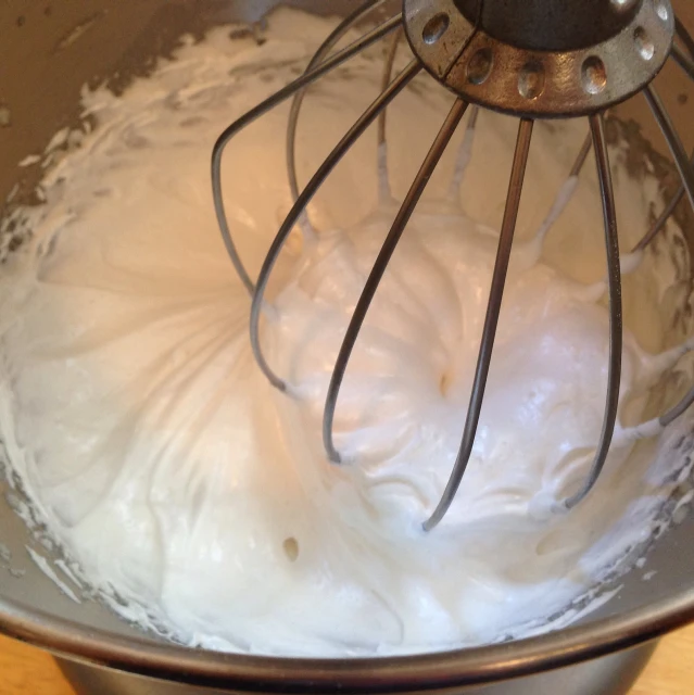 a mixer is mixing up white cream on a table