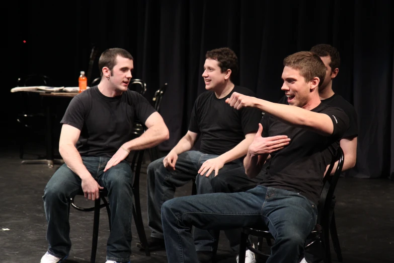 three young men sitting on chairs in front of a curtain