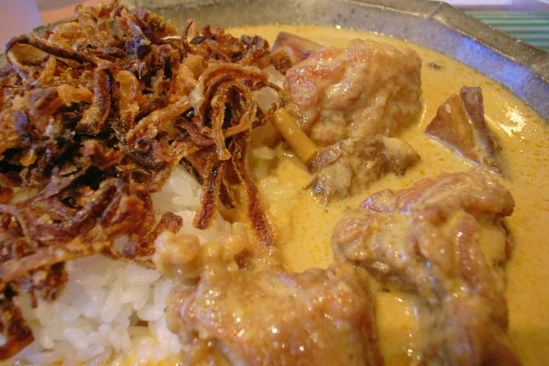 a silver bowl with rice, meat and gravy in it