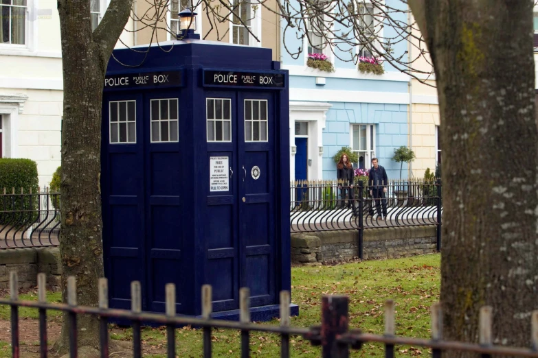 a blue telephone booth on the side of a street