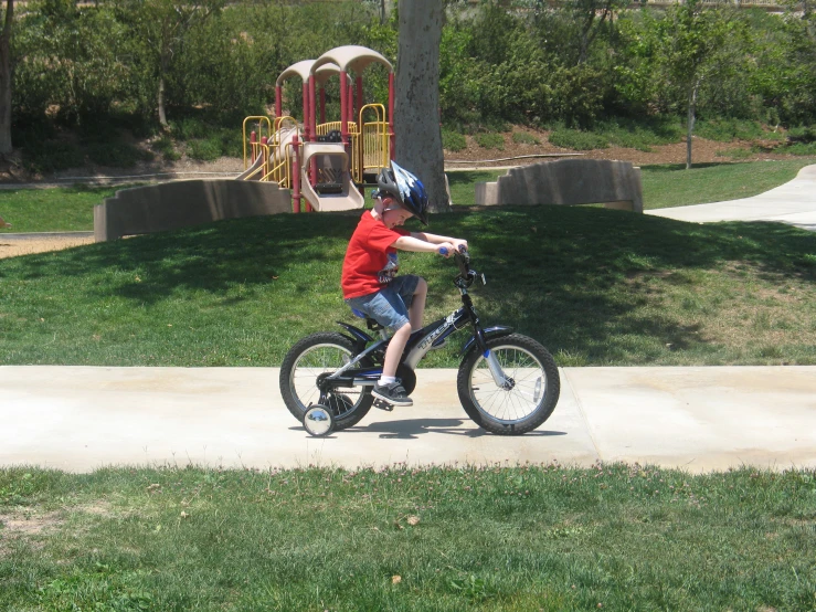 a small boy on a bike near some swings