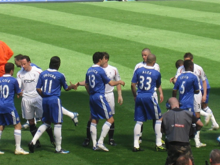 a group of men wearing blue and white uniforms standing on a soccer field
