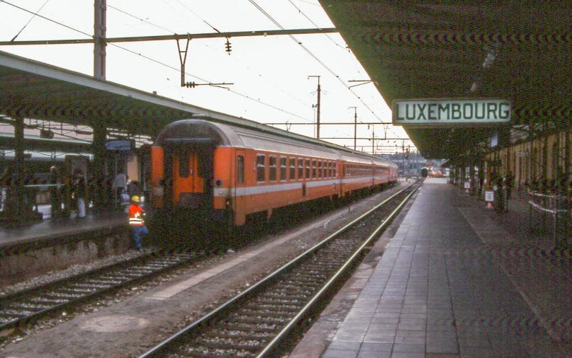 an orange train pulls into the platform at the station