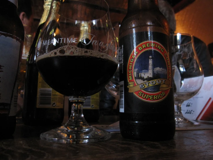a dark beer sits on a table with a bottle and glass