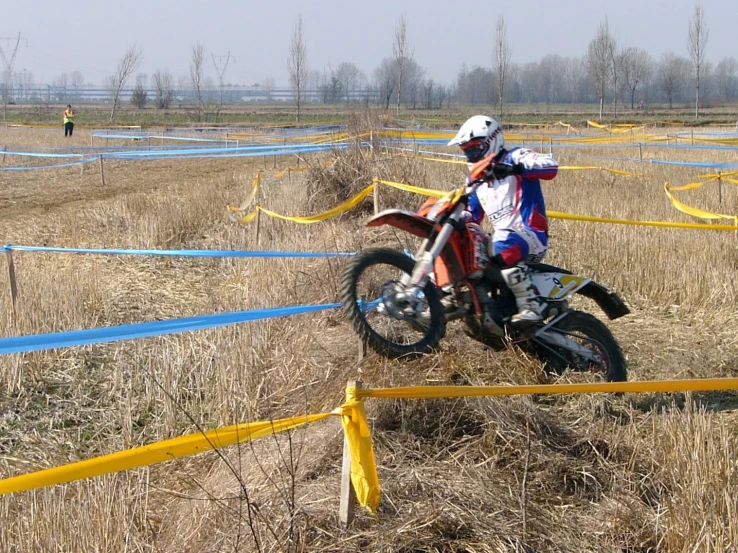 a motorcyclist riding a dirt bike through tall grass