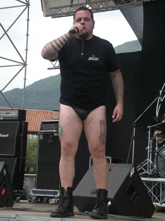 a man standing in front of a stage wearing tattoos