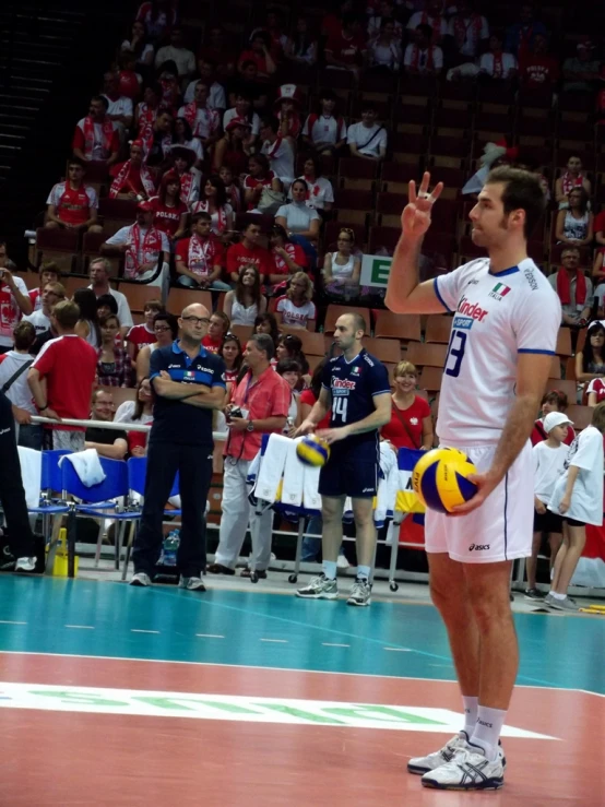 a man wearing white shorts and a white shirt, holding a ball in his left hand