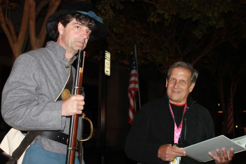 an older man with a hat and two other men holding flags