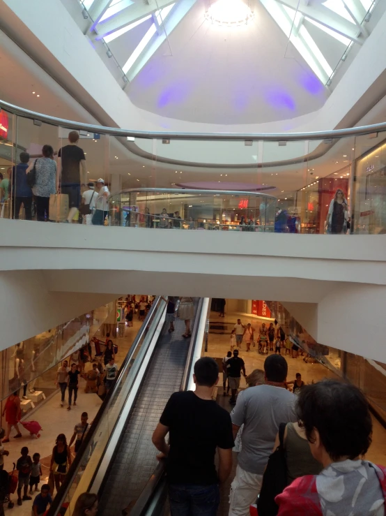people are walking down an escalator in a shopping mall