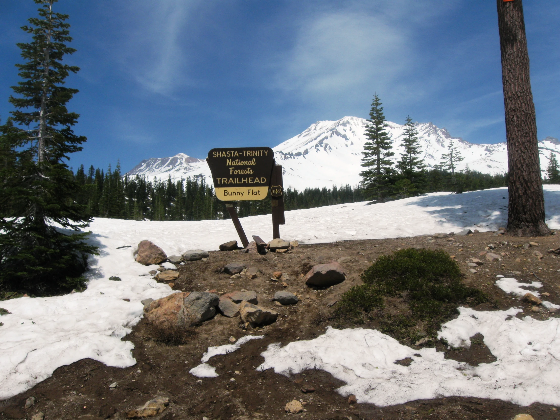 a sign is sitting in the snow next to some trees