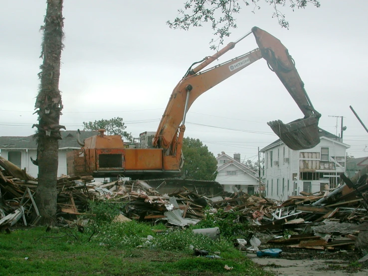 an excavator demolishing up rubble from the side of a road