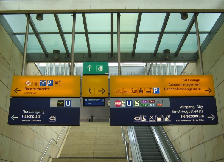 a couple of signs mounted to the side of an escalator