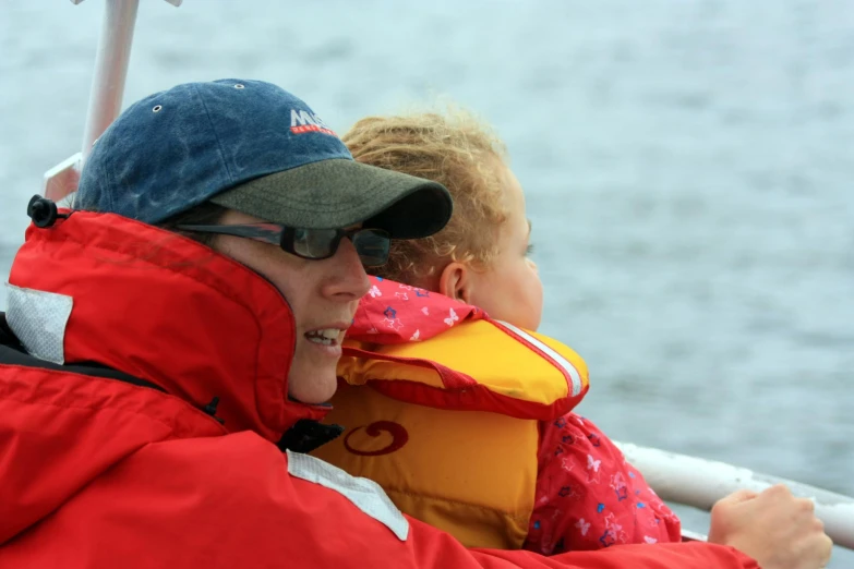 a man in red coat with sunglasses on holding a child