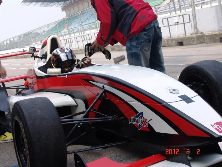 a man standing next to a racing car in a pit