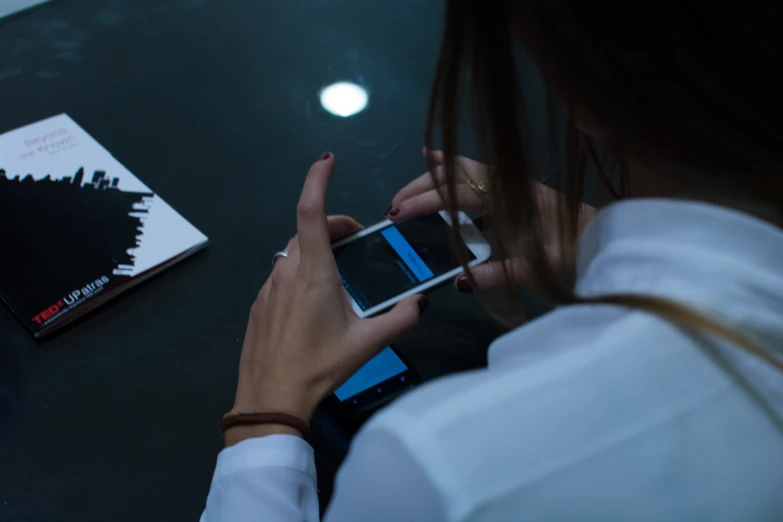 a person sitting at a table looking at a cell phone