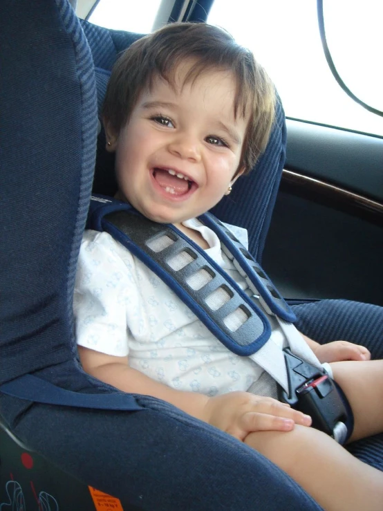 a small child in a car seat holding a leash