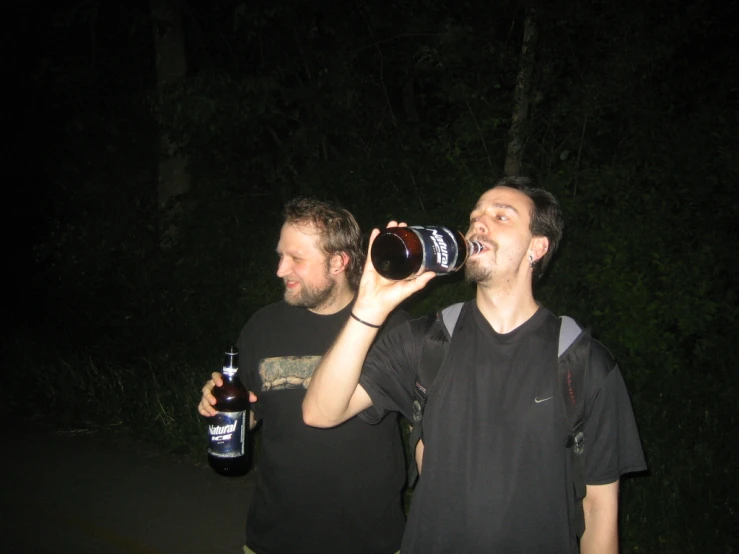 a pair of men drinking from beer bottles