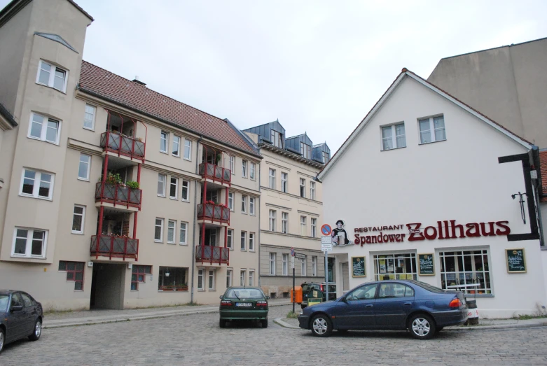 cars parked in front of buildings on cobblestone street