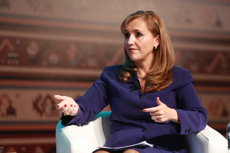 a woman wearing a purple blazer is talking to someone