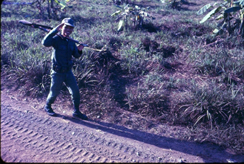 a young man with a baseball bat walks in the dirt