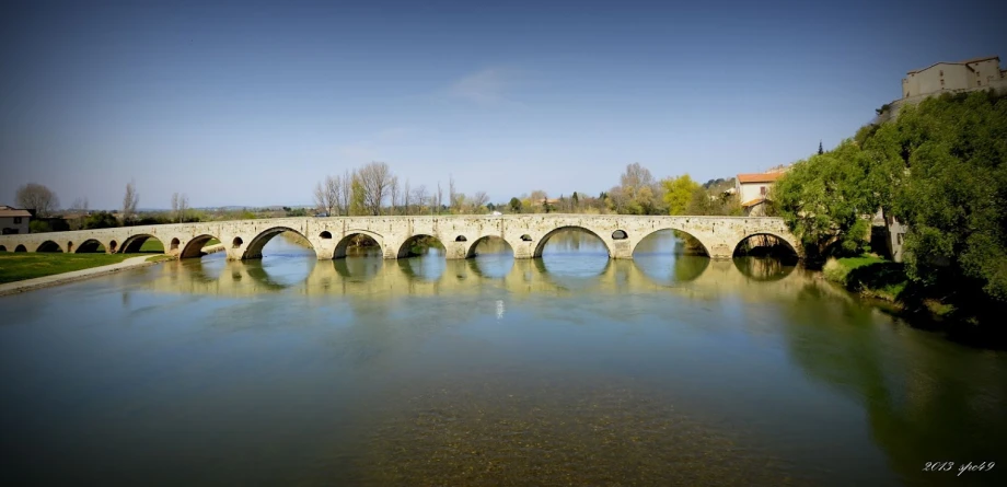 an old stone bridge is shown over a lake