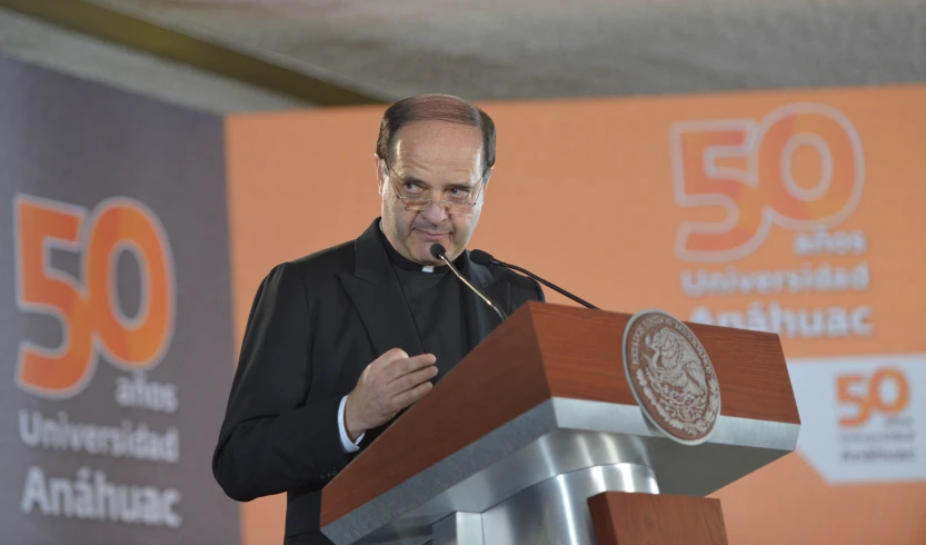 a man at a podium giving a speech with the logo 50 in the background