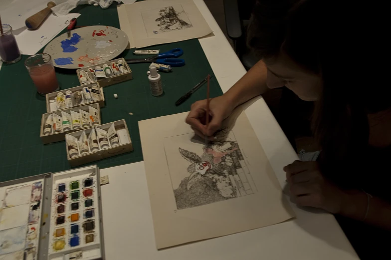 woman doing artwork on table with various pieces