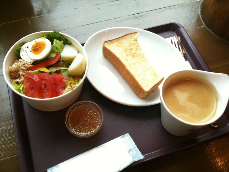 a meal sits on the tray on top of a wooden table