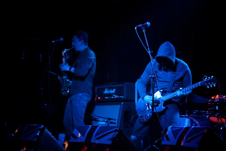 two guys playing guitar and a trumpet in the dark