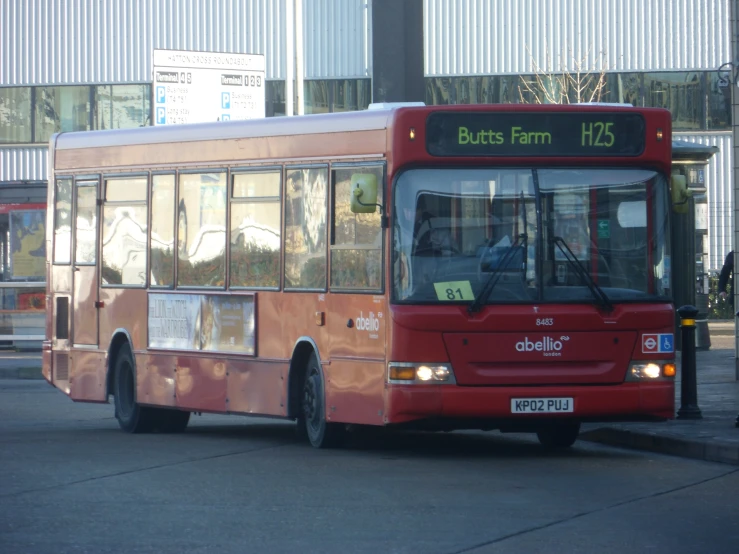 a red bus driving on the road in front of a building