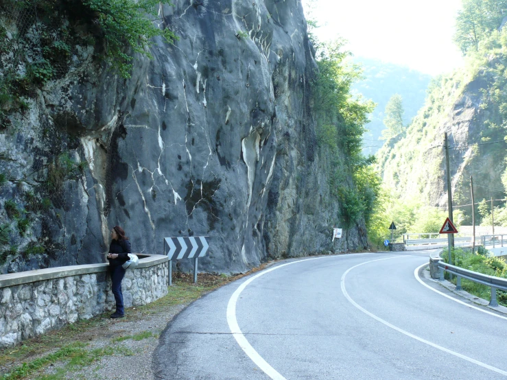 a person stands by the side of a winding road