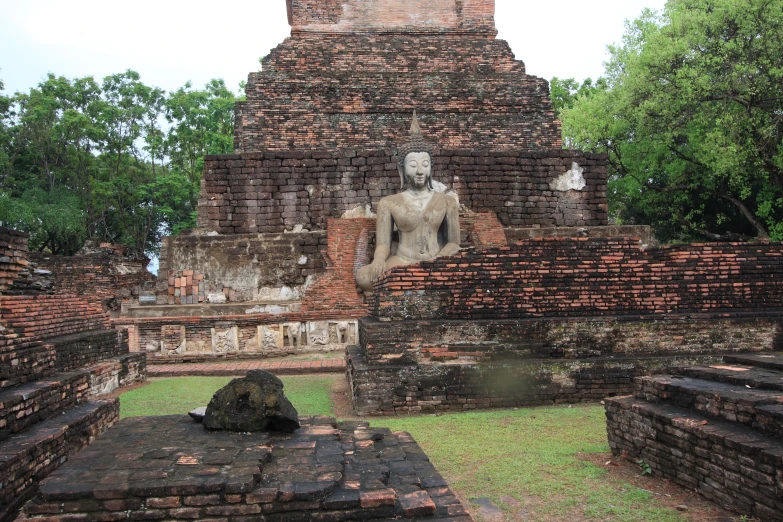 an ancient building in the middle of a park with a statue on it