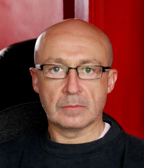 a bald man sitting in a chair wearing glasses