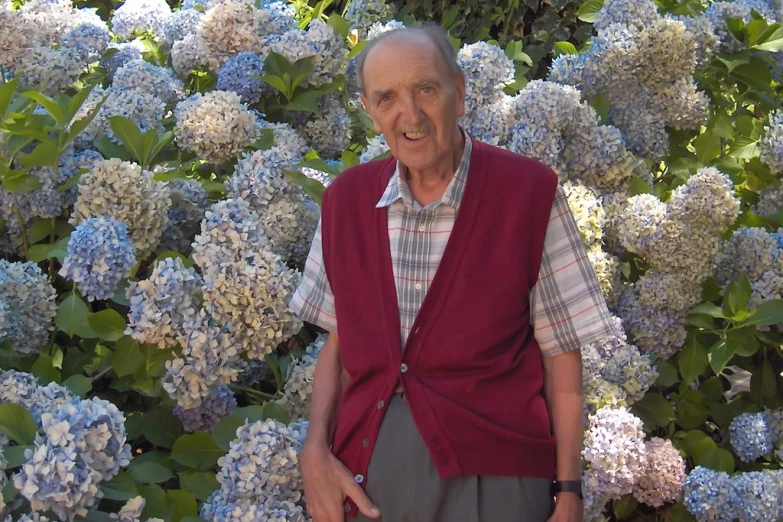 an older man stands in front of flowers