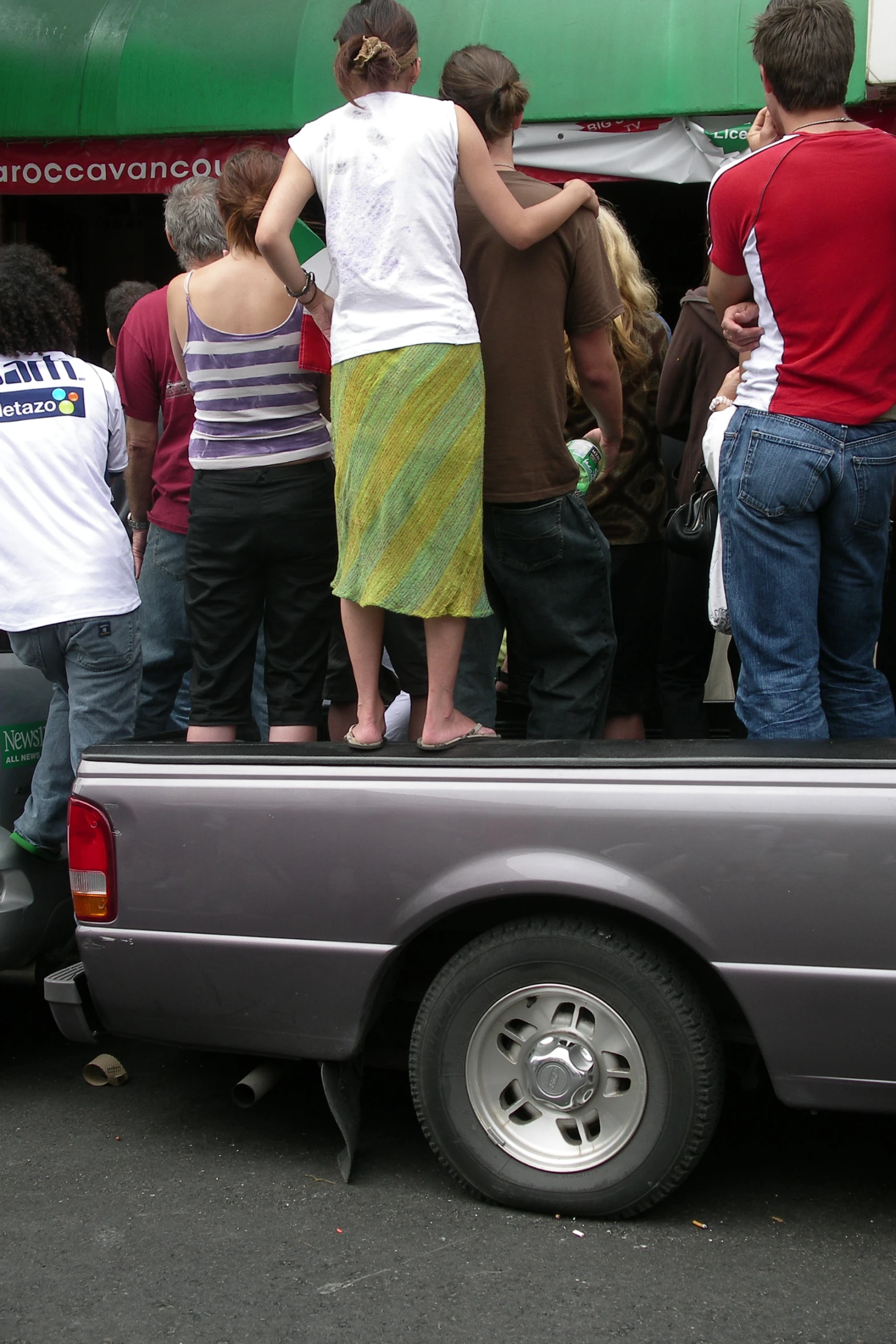 people in the back of the pickup truck with their back to a person standing behind them