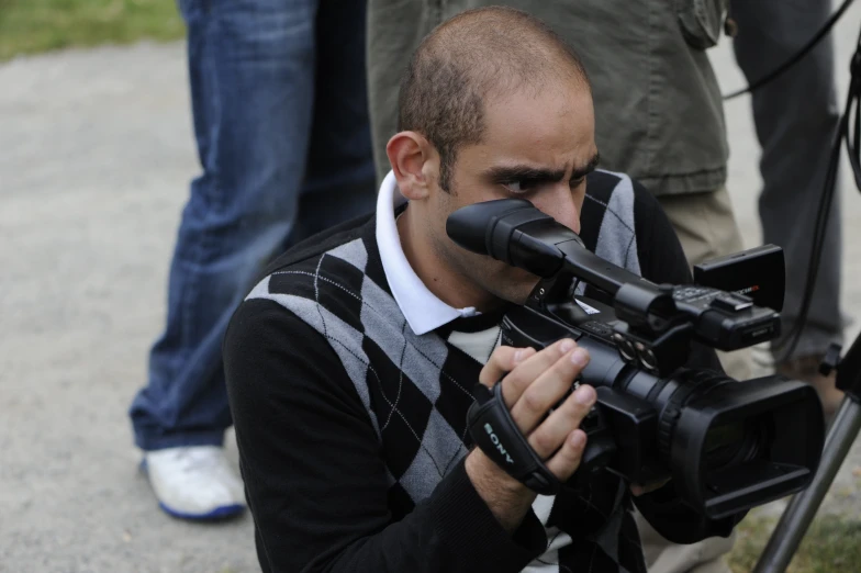 a man with an arm around a camera is squatting down