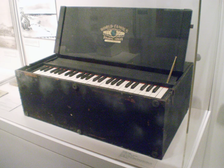 an old black piano set on display in a case