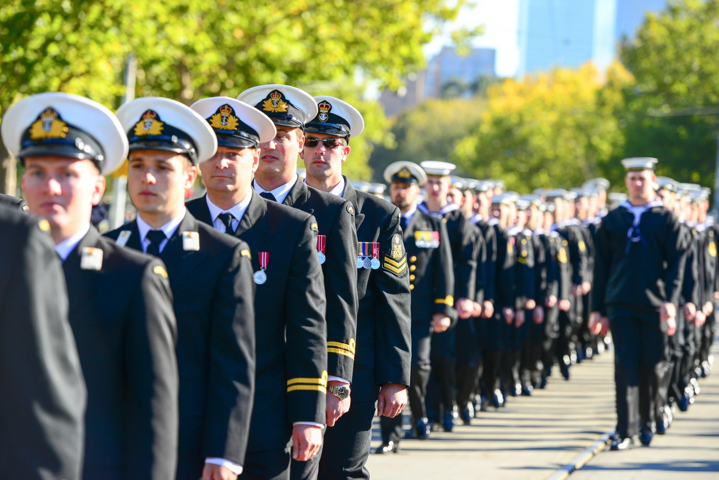 men in military uniforms march in formation on a city street