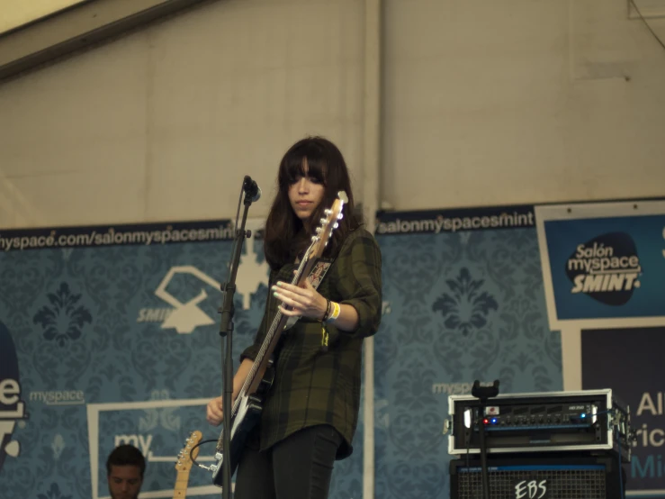 a woman holding onto a guitar while standing on a stage