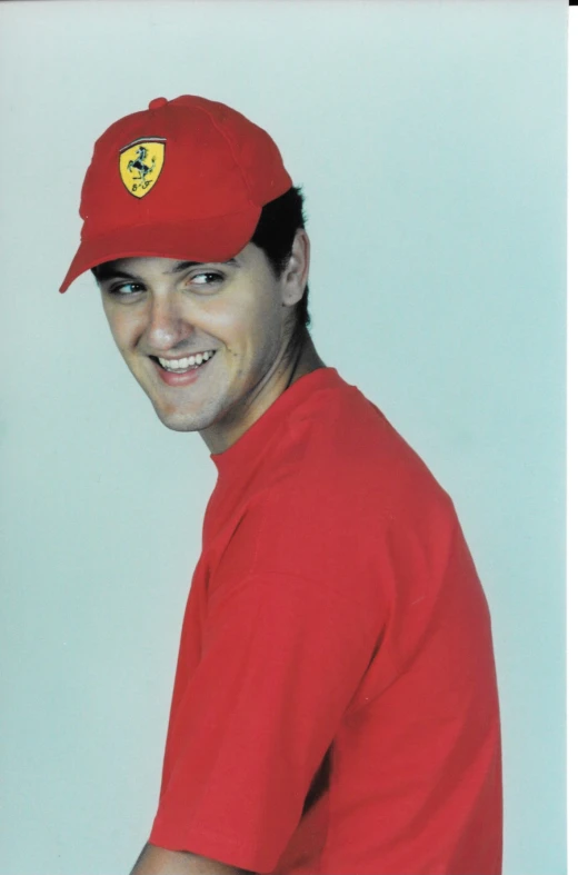 a man in a red shirt and hat smiling at the camera