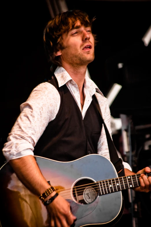a man in a vest playing a guitar