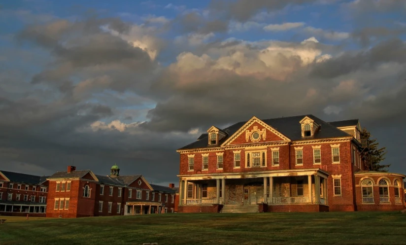 large brick building in an area of green grass under cloudy skies