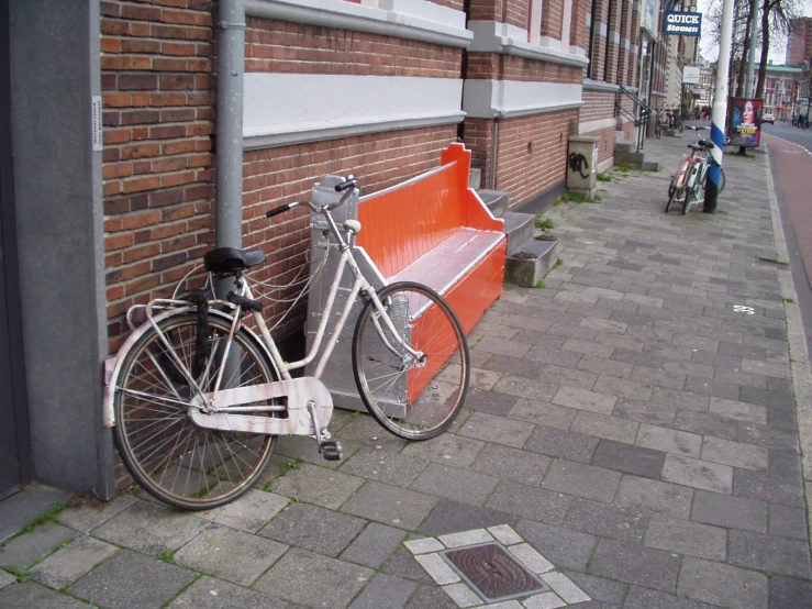 two bikes are parked on the sidewalk by the building