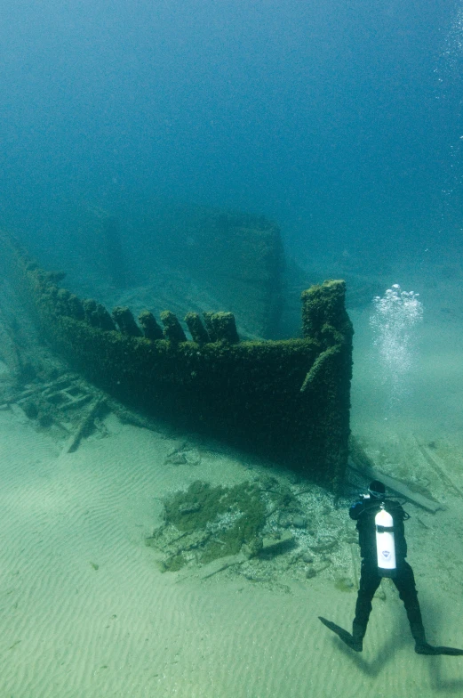 a man standing in the water next to an old ship