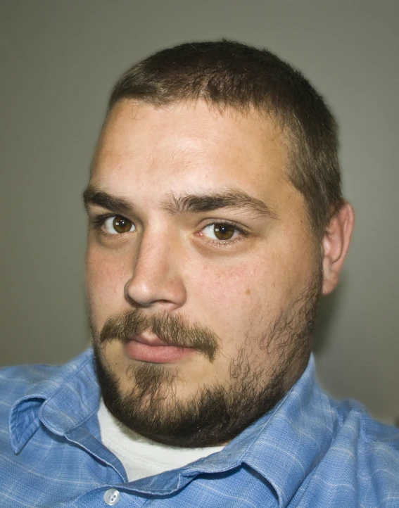 a man is wearing a blue shirt with a beard