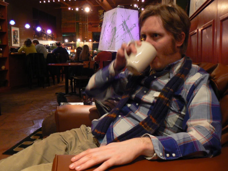 the young man is sipping a coffee in a bar