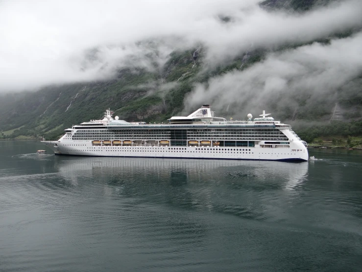 a cruise ship is docked on the water near the mountains